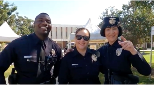 Three smiling LAPD officers, one African American male, one white woman and one Asian American woman. Asian woman.