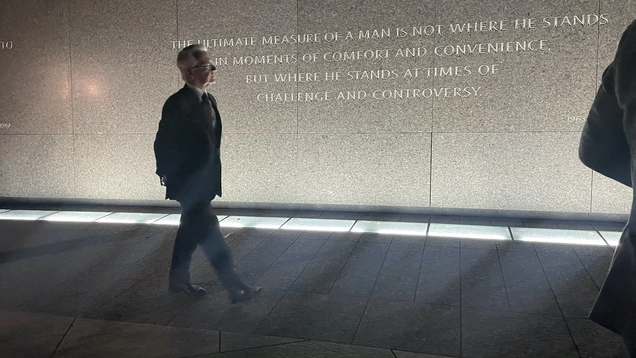 After dark, Council President walks past inscription at Dr. King Monument. reading, "The ultimate measure of a man is not where he stands in moments of comfort and convenience, but where he stands at times of challenge and controversy."